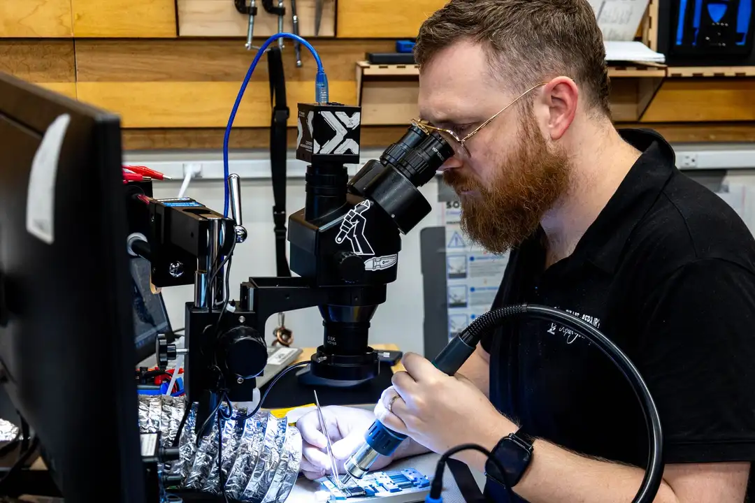 An instructor soldering a board at a microscope station